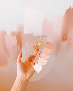 a person's hand holding a piece of paint in front of a pink wall