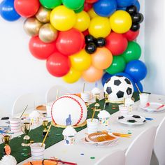 a table topped with lots of different colored balloons and desserts on top of it