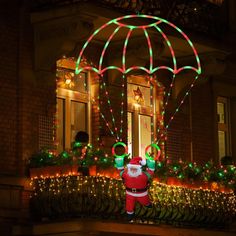 a man dressed as santa claus is in front of a house decorated with christmas lights