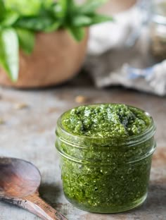 a jar filled with green pestle next to a wooden spoon