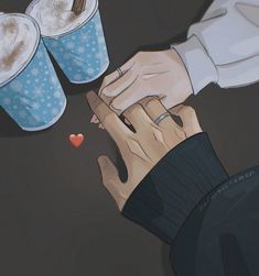 two people are holding hands over some cups with coffee in them and one has a heart on it