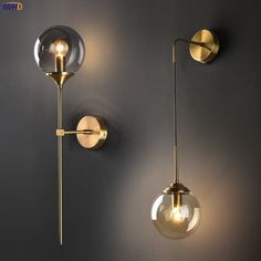 two wall lights on the side of a gray wall, one is gold and the other is clear