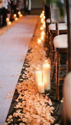 two candles are sitting on the ground next to some chairs with flowers and leaves all over them