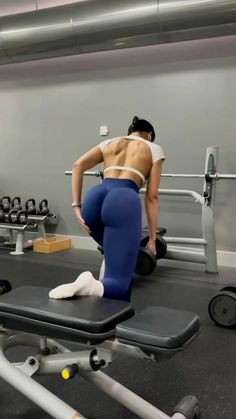 a woman in blue leggings standing on a bench with her back to the camera