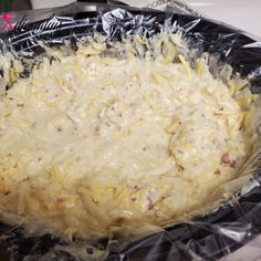 an uncooked casserole dish in plastic wrap on a stove top with utensils