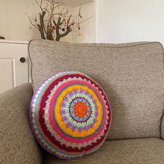 a round crocheted pillow sitting on the back of a couch in a living room