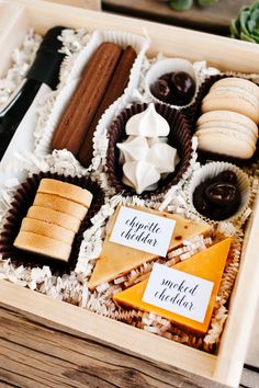 a wooden box filled with lots of different types of cheese and crackers on top of it