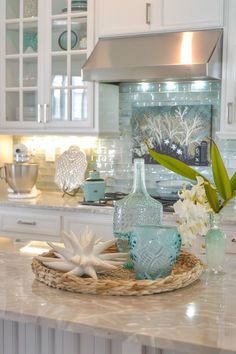 a kitchen with white cabinets and blue glass vases on the counter top, along with other items