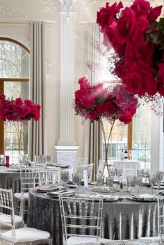 the tables are set with silver linens and pink flowers in vases on them