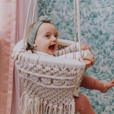 a baby is sitting in a swing and smiling