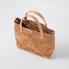 The Natural Derby Mini Tote is the perfect everyday tote, handmade in the USA with heirloom-quality craftsmanship and beautiful full-grain leather. Natural Derby is a smooth-grained leather with a waxed finish, good stand-up, thick but not stiff temper, and dimensional natural color with dramatic pull-up, produced by the Horween tannery in Chicago. The Natural Derby Mini Tote comes standard with Russet handles. Classic Everyday Shoulder Bag With Waxed Finish, Classic Vegetable-tanned Leather Bags, Everyday Bag In Bridle Leather With Smooth Grain, Everyday Shoulder Bag With Oiled Leather And Leather Lining, Everyday Shoulder Bag In Bridle Leather With Leather Lining, Everyday Shoulder Bag With Bridle Leather And Leather Lining, Classic Everyday Shoulder Bag In Oiled Leather, Everyday Oiled Leather Shoulder Bag With Leather Lining, Waxed Bridle Leather Bag For Everyday Use