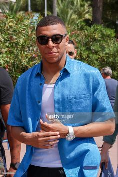 a man wearing sunglasses and a blue shirt is seen walking in the street with other people behind him