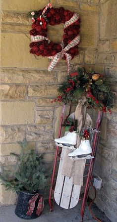 a wooden sled sitting next to a christmas wreath on top of a brick wall