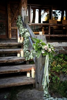 a bunch of candles that are sitting on some steps with flowers and greenery around them