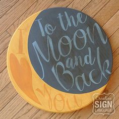 a black and yellow painted wooden sign that says to the moon and back on it