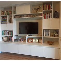 the entertainment center has bookshelves and shelves with pictures on each shelf, along with a flat screen tv