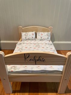 a small wooden bed with a name on the bottom and side rails that are attached to it