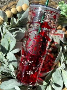 a red starbucks cup sitting on top of a pile of leaves