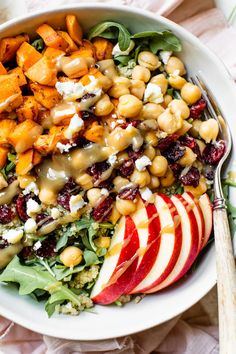 an apple and chickpeas salad with dressing in a white bowl on a table