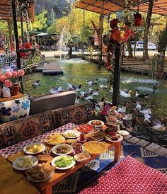 a picnic table with food on it in front of a pond