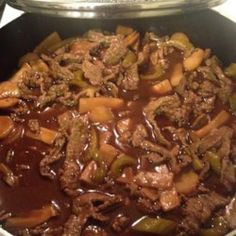 beef and vegetables are being cooked in a skillet on the stove top, ready to be eaten