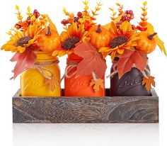 three mason jars filled with fall leaves and pumpkins are sitting on a wooden tray