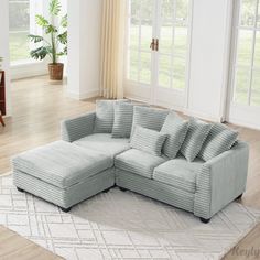 a large sectional couch sitting on top of a rug in a living room next to a window