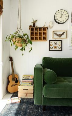 a green couch sitting in a living room next to a clock