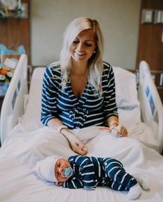 a woman sitting in a hospital bed with a baby laying on it's side