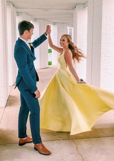 a man in a blue suit and yellow dress dancing with a woman in a yellow dress