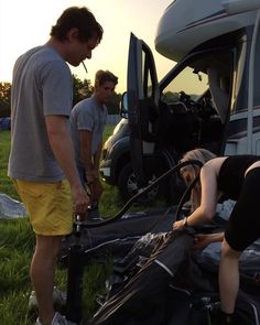 two men standing next to each other in front of a camper with the door open