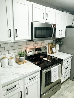 a kitchen with white cabinets and marble counter tops, stainless steel appliances and black stove top oven