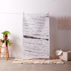 a white wall hanging next to a wooden chair and potted plant in a room