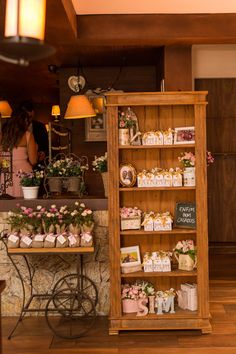 a wooden shelf filled with lots of small boxes and flowers on top of a table