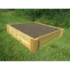 a wooden raised garden bed with dirt in the middle and grass on the ground next to it