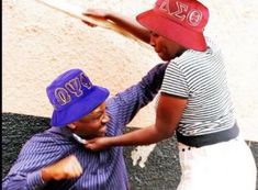 two men wearing hats and one is brushing the other's hair with his hand