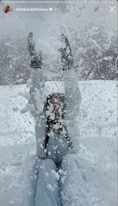 a person is sitting in the snow with their feet up and arms out to the side