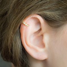 a woman's ear is shown with three small beads on the end of it