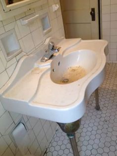 a white sink sitting under a bathroom mirror next to a tiled floor and wall mounted faucet