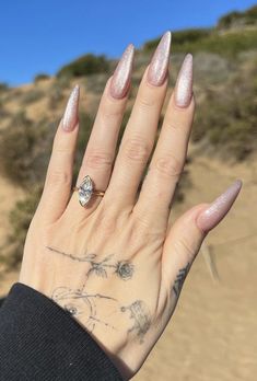 a woman's hand with pink nail polish and a diamond ring on her finger