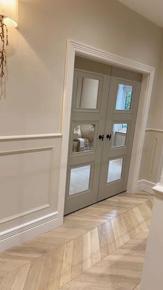 an empty hallway with two doors leading into the living room and dining room in the background