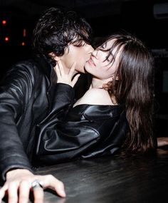 a man and woman kissing each other in front of a table