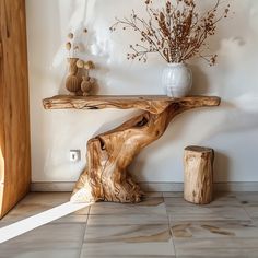 a wooden table sitting on top of a tiled floor next to a white vase filled with flowers