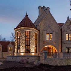 a large stone house lit up at night with lights on the front and side windows