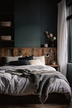 a large bed sitting in a bedroom next to a window with curtains on the windowsill