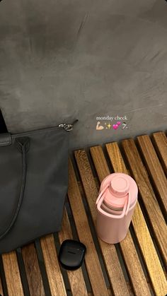 a gray bag and a pink cup on a wooden table