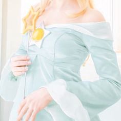 a woman with blonde hair wearing a blue dress and holding a flower in her hand