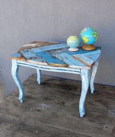 an old table is painted blue and has a small globe on top of the table