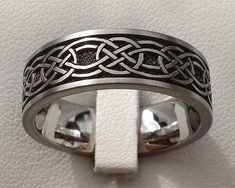 a wedding ring with an intricate design on the outside and inside, sitting on a white surface