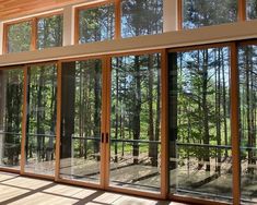 an empty room with lots of windows and wood flooring in front of the trees